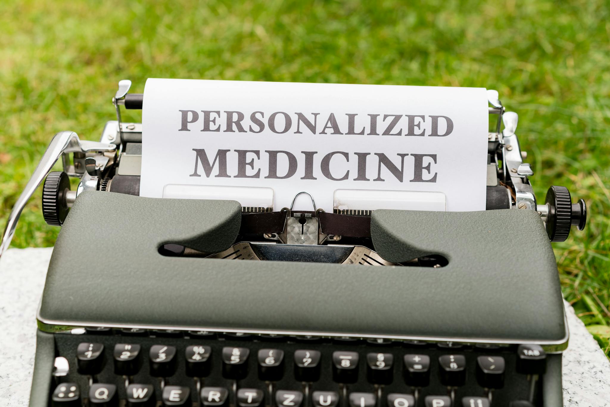 A vintage typewriter outdoors displaying a paper with the text 'Personalized Medicine'.